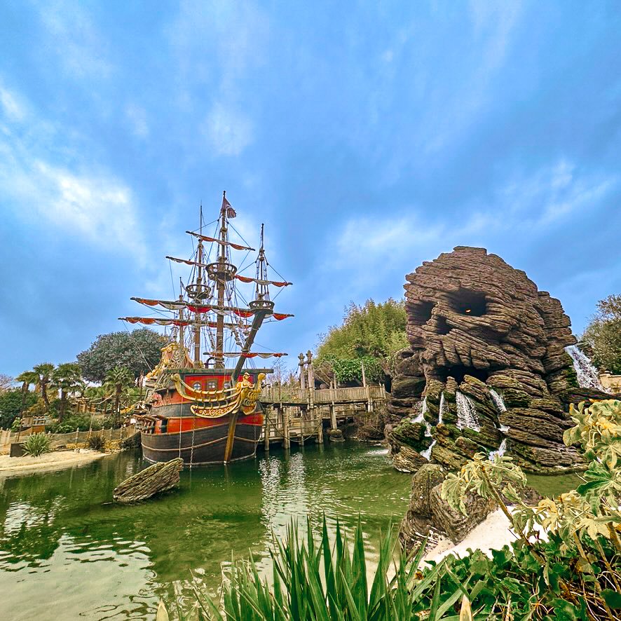 Adventureland at Disneyland Paris featuring the pirate ship and Skull Rock waterfall on a sunny day